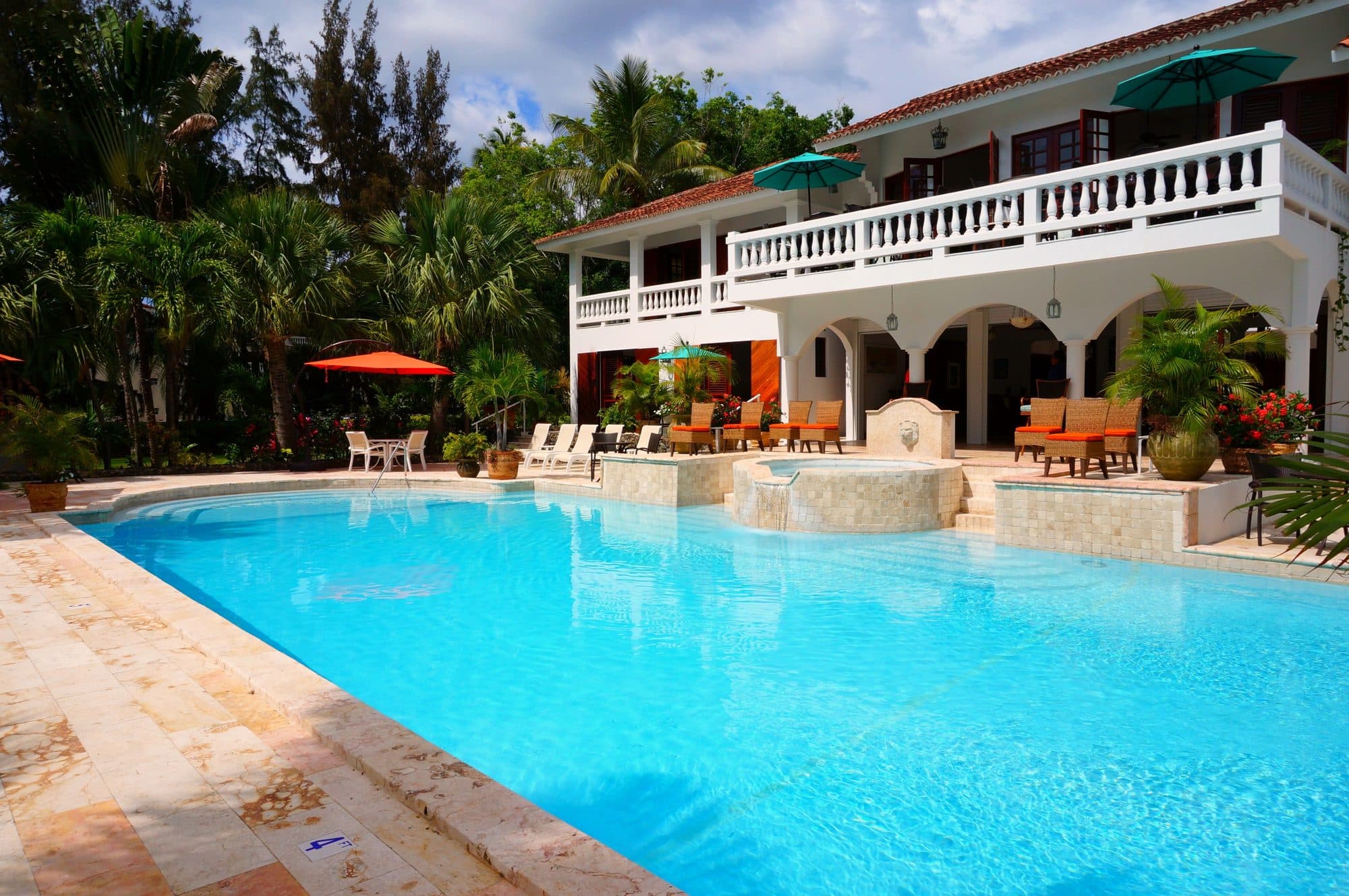 Casa de dos pisos con terraza y una alberca grande, rodeada de palmeras (foto ilustrativa)